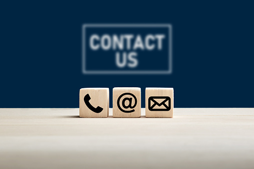 contact Phone and e-mail icons on wooden cubes with contact us text on blue background. Website page contact us or e-mail marketing concept.